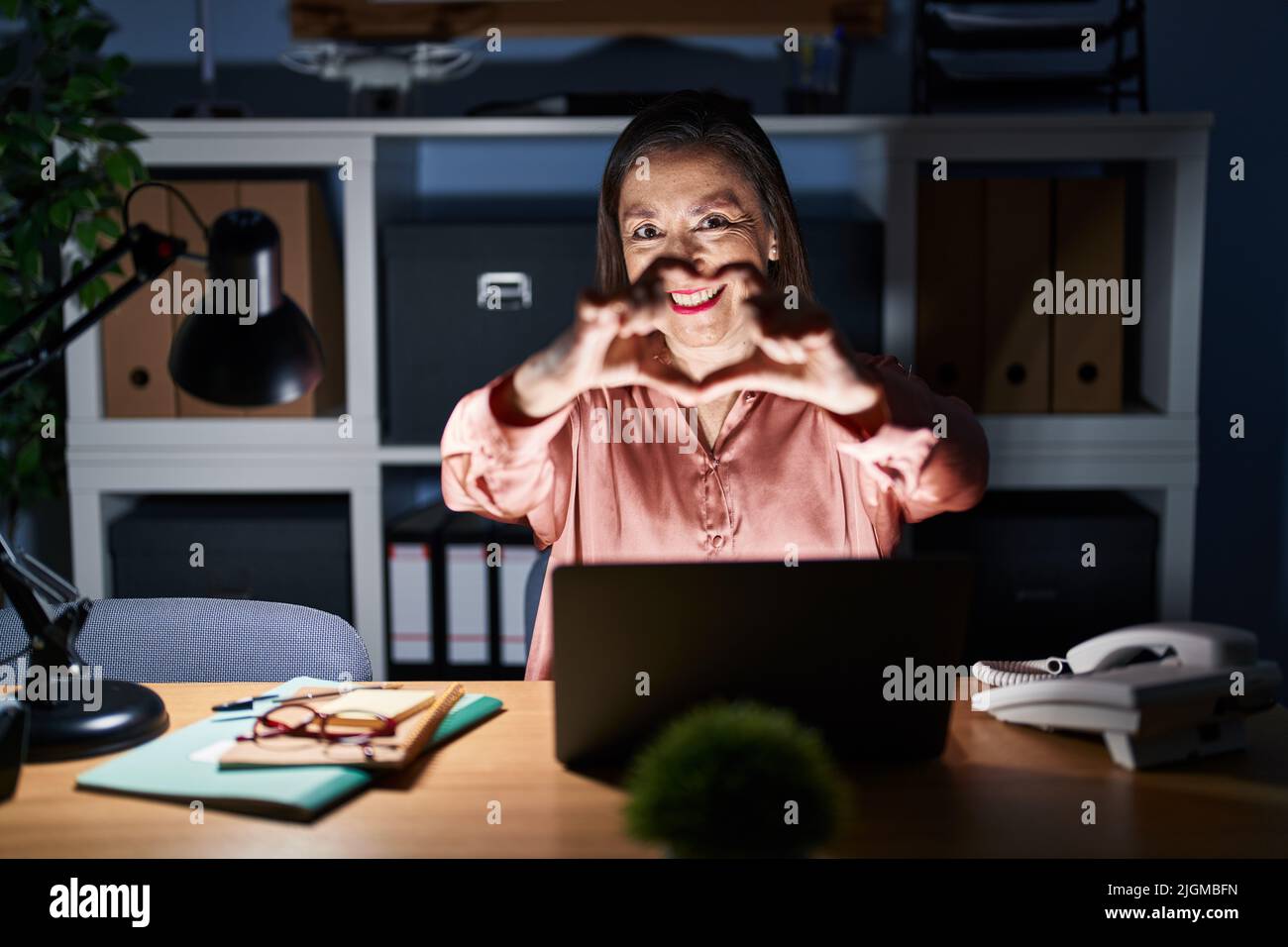 Middle age hispanic woman working using computer laptop late at night ...
