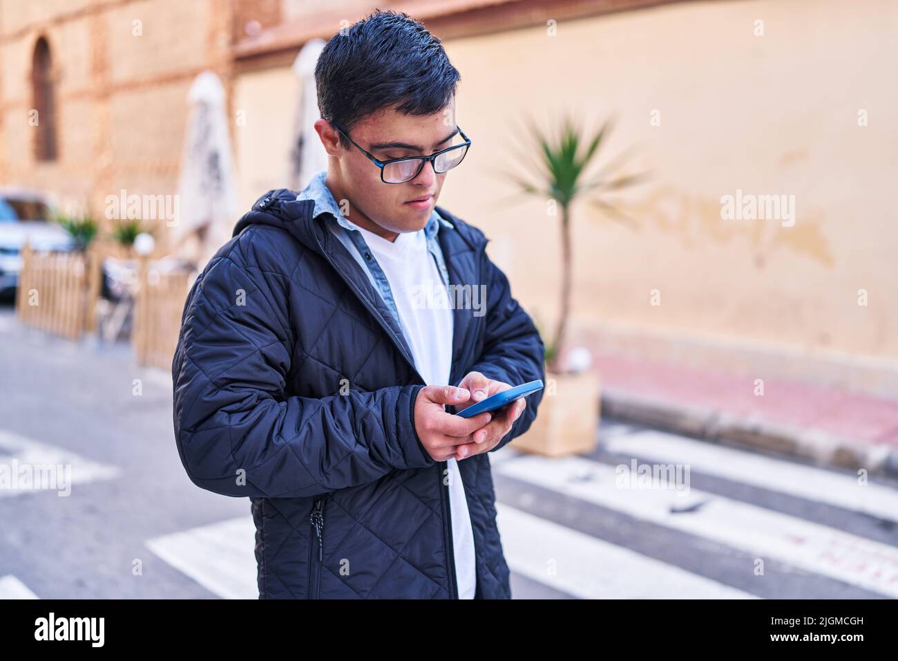 Down syndrome man using smartphone at street Stock Photo