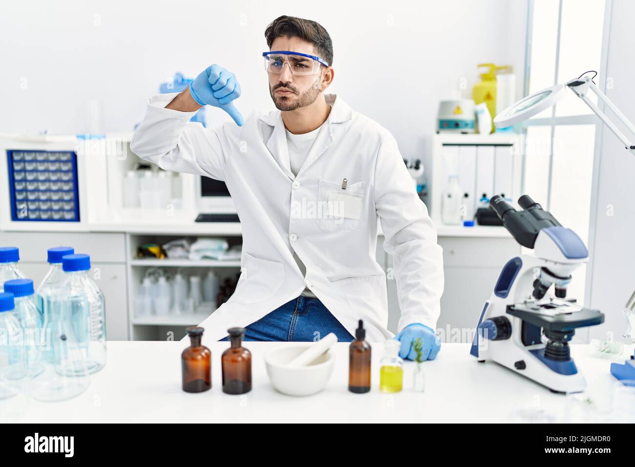 Young hispanic man working at scientist laboratory with angry face ...