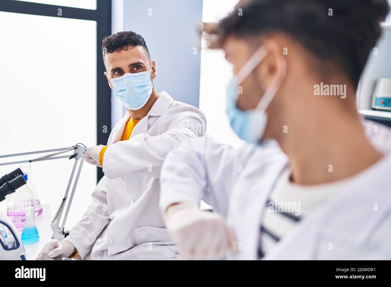 Two man scientists doing elbow greeting at laboratory Stock Photo