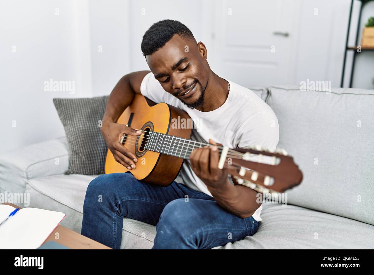 Young african american man smiling confident playing guitar at home ...