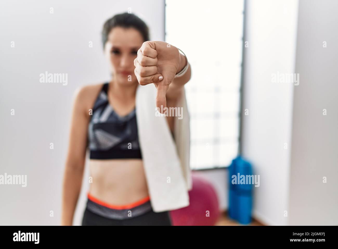 Young brunette woman wearing sportswear and towel at the gym looking ...