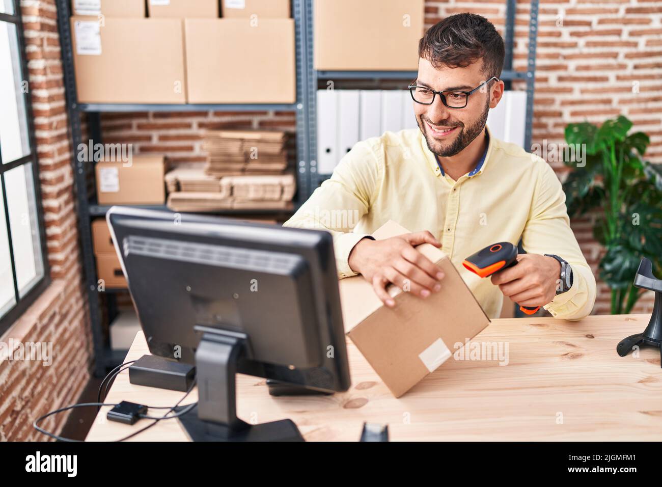 Young hispanic man ecommerce business worker scanning label using barcode reader at office Stock Photo
