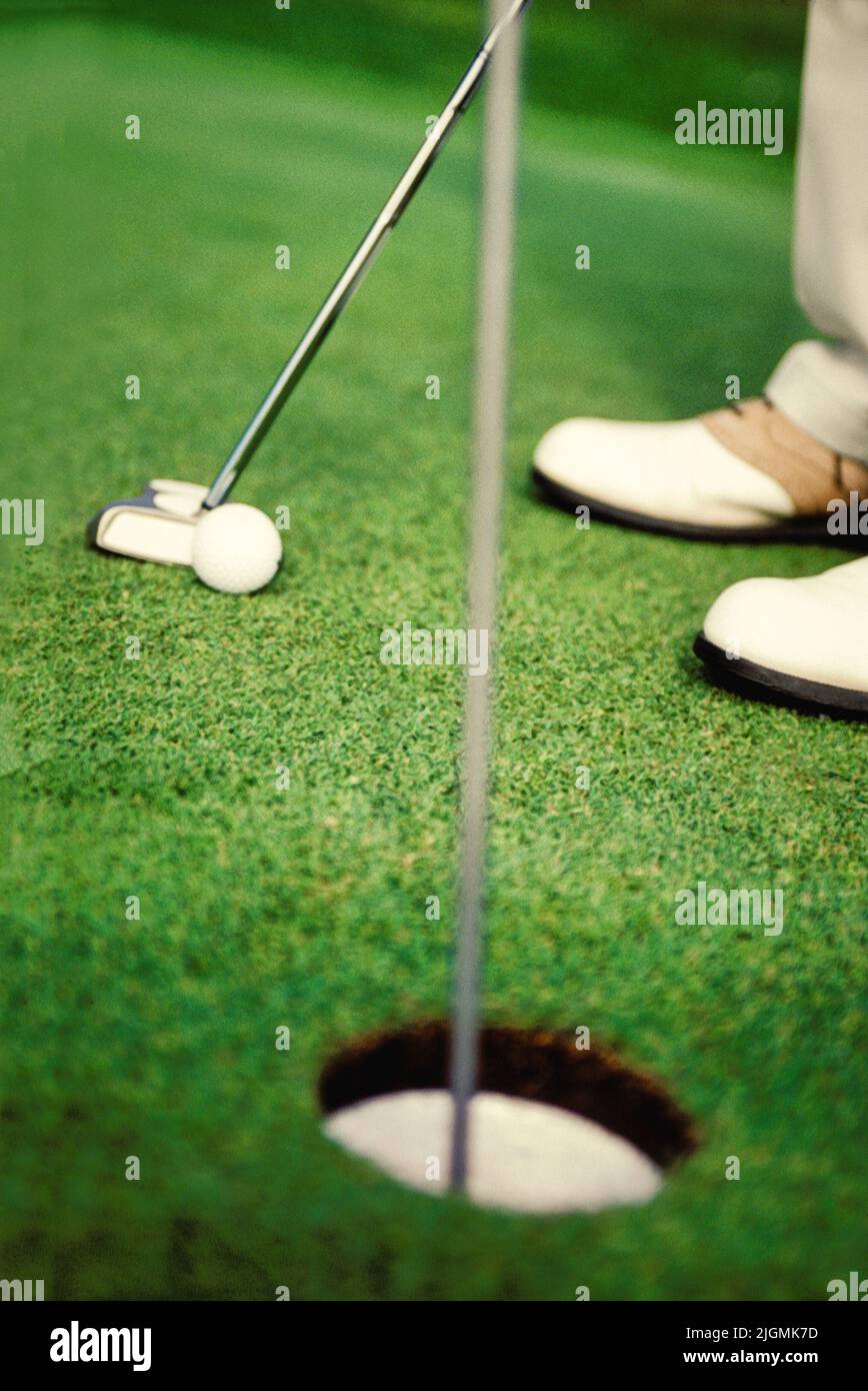 A golfer lines up a putt on a practice green. Stock Photo