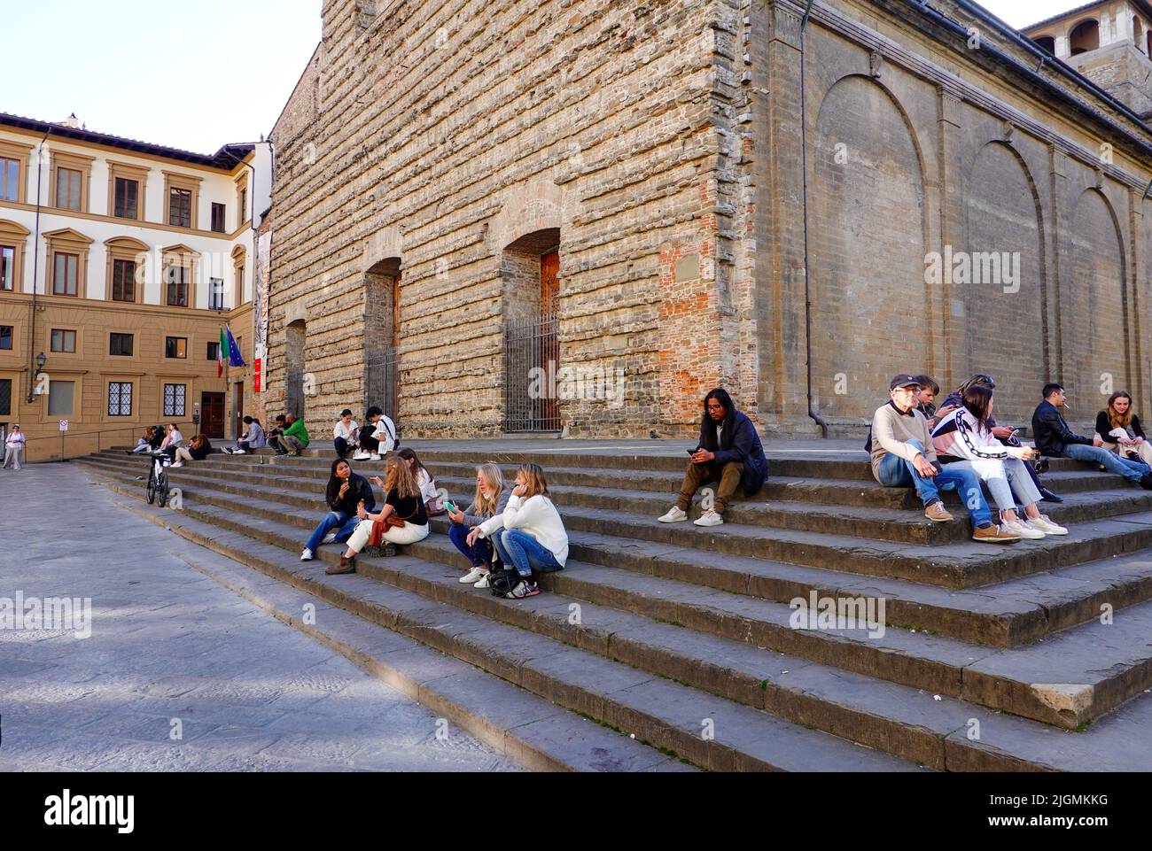 People sitting on the steps outside the Basilica di San Lorenzo, burial place of all the principal members of the Medici family, Florence, Italy. Stock Photo