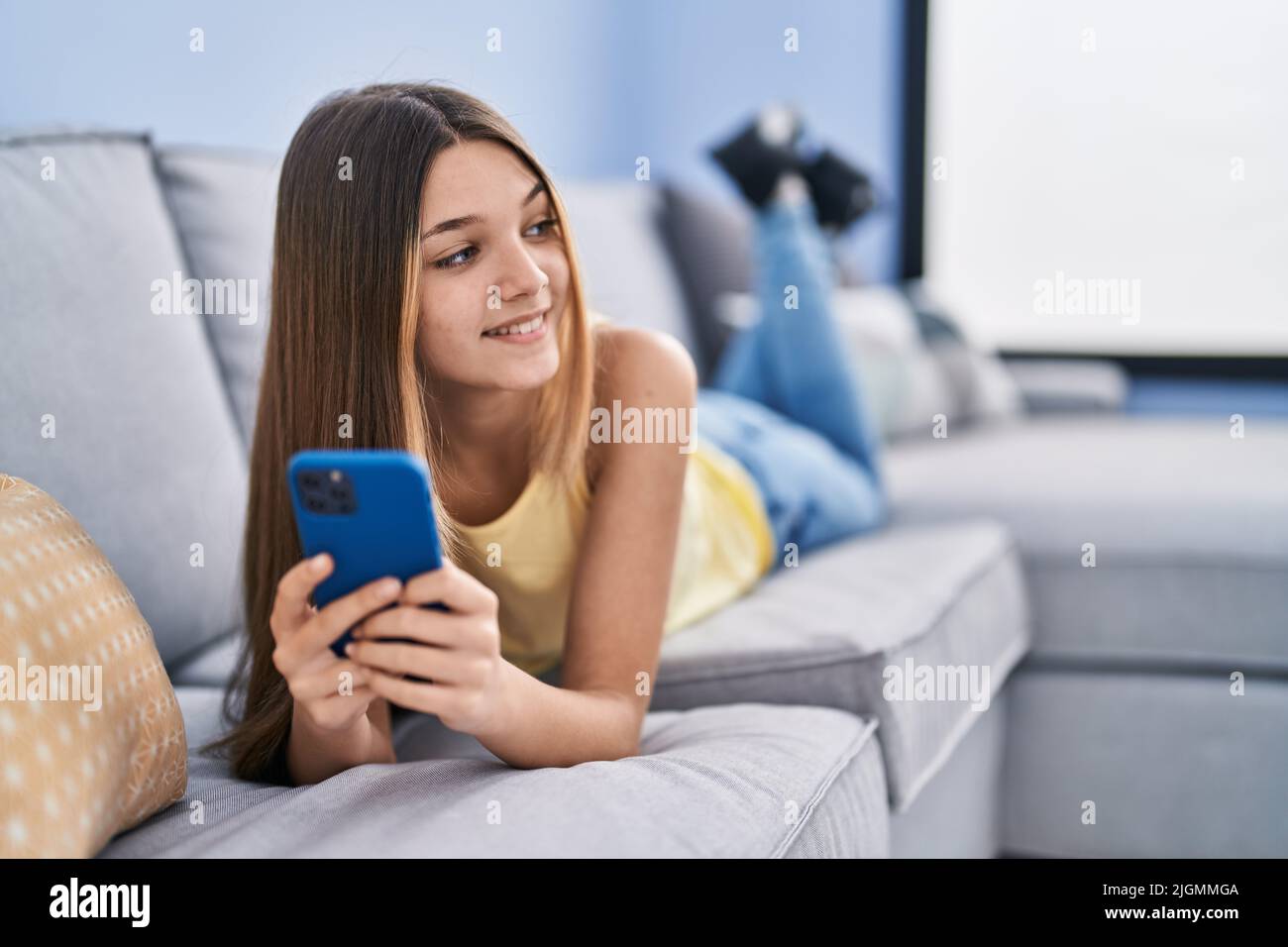 Adorable girl using smartphone lying on sofa at home Stock Photo - Alamy
