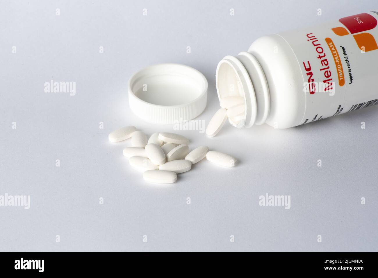 Davis, CA, July 9, 2022. Bottle of CNC Melatonin time-release 3mg against white background, turned, pills spilling out. Melatonin is a hormone used to Stock Photo