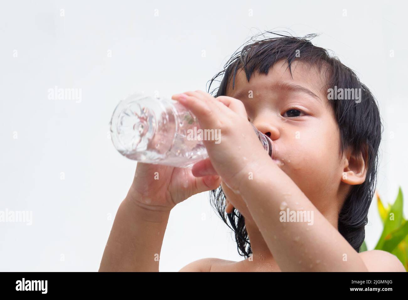 thirsty asian boy drinking fresh water from plastic bottle after finish playing with friend in the hot weather day on summer. Stock Photo