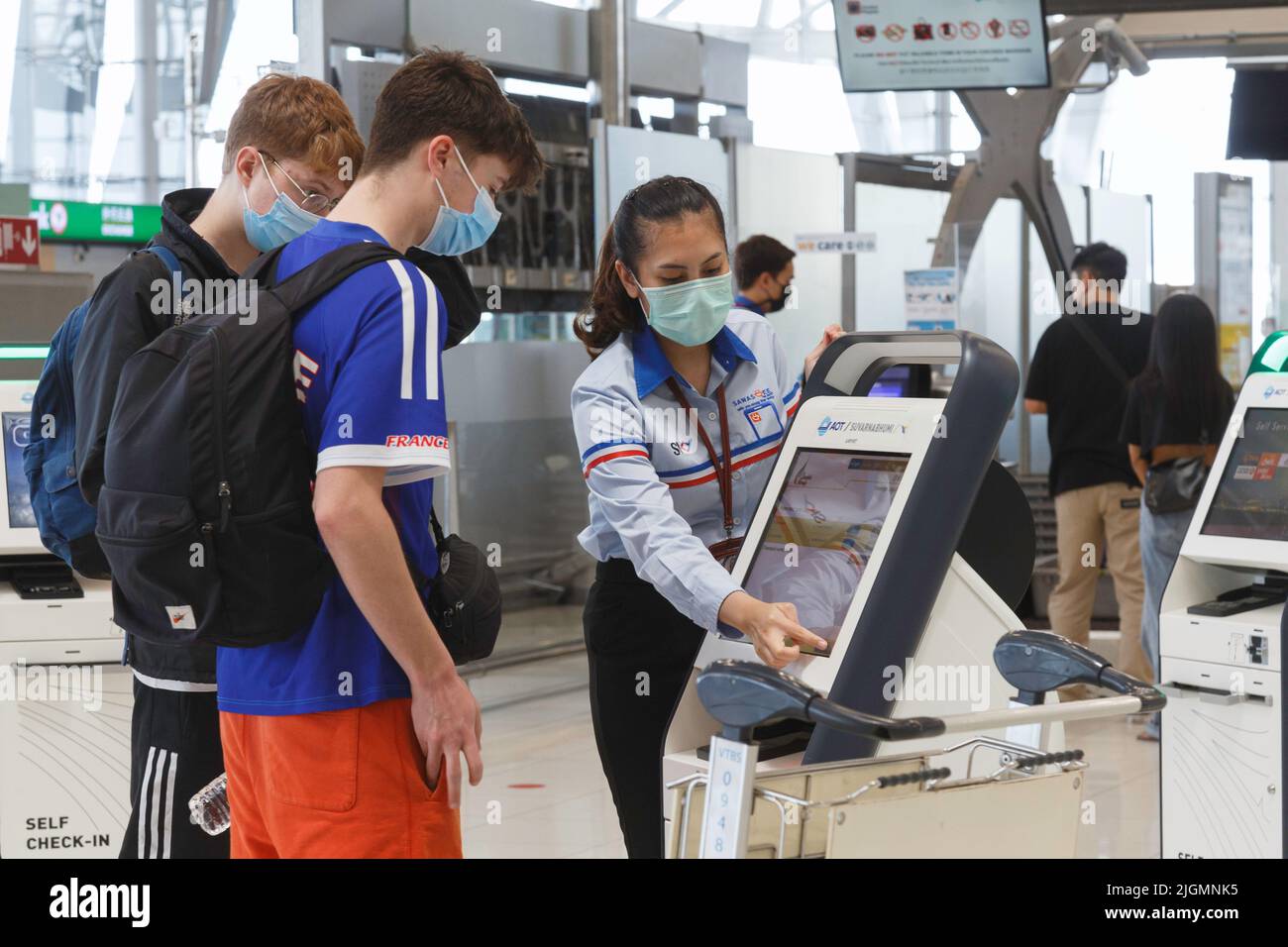 Bangkok, Thailand - May 7, 2022 : Asian airport service officer help teenager tourist visitors to self service check-in machine at suvarnabhumi airpor Stock Photo