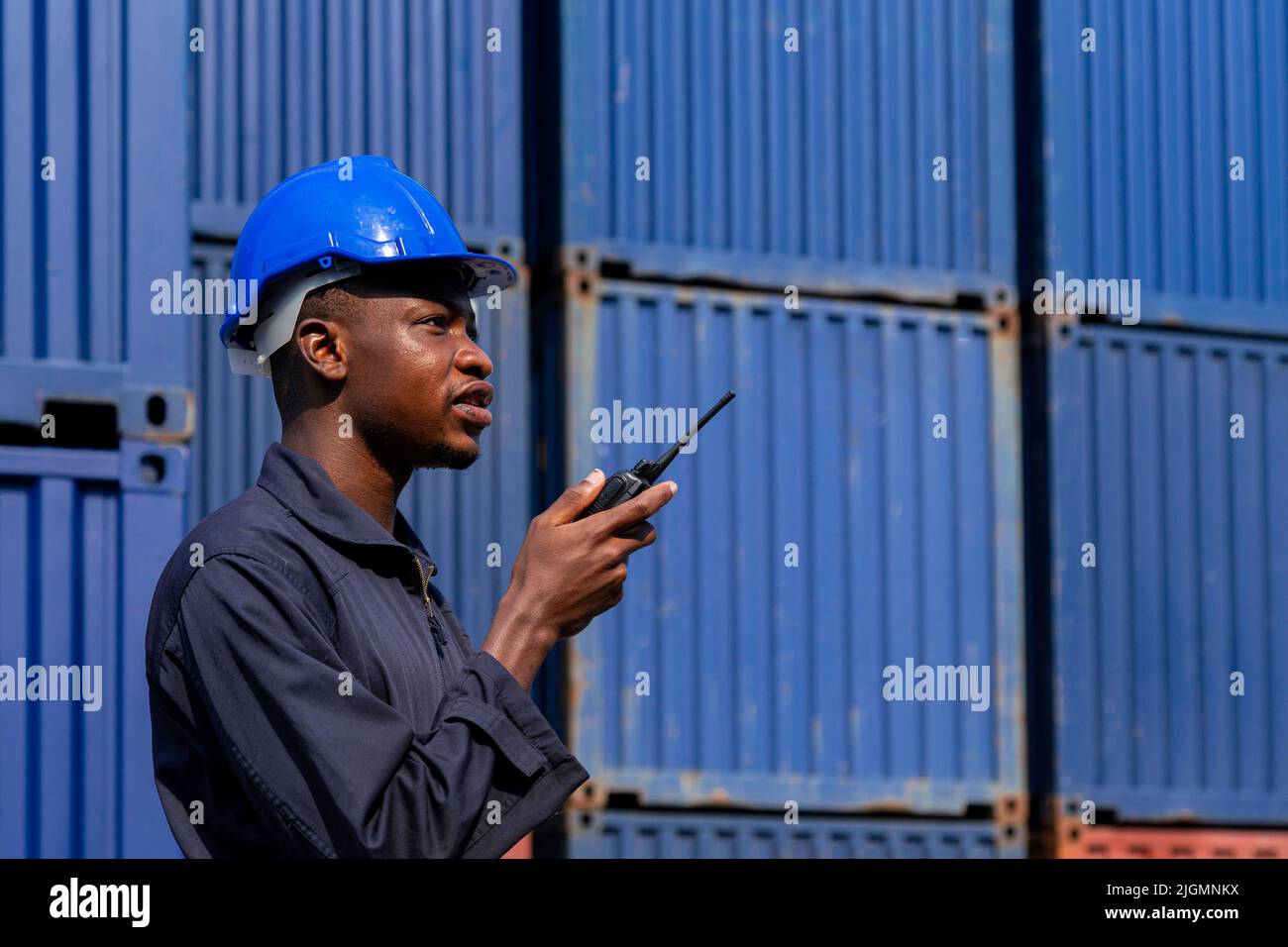 black african amarican man worker working control loading freight containers at commercial shipping dock. cargo freight dock and import export logisti Stock Photo