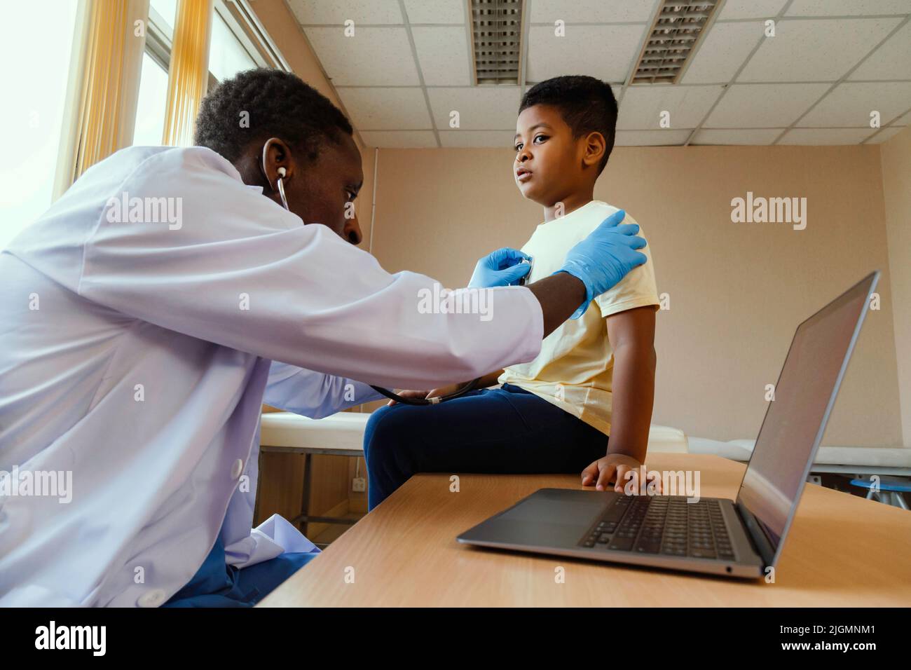 african american man pediatrician doctor using stethoscope to examining little boy from sickness in the office at the hospital. medical and healthy li Stock Photo