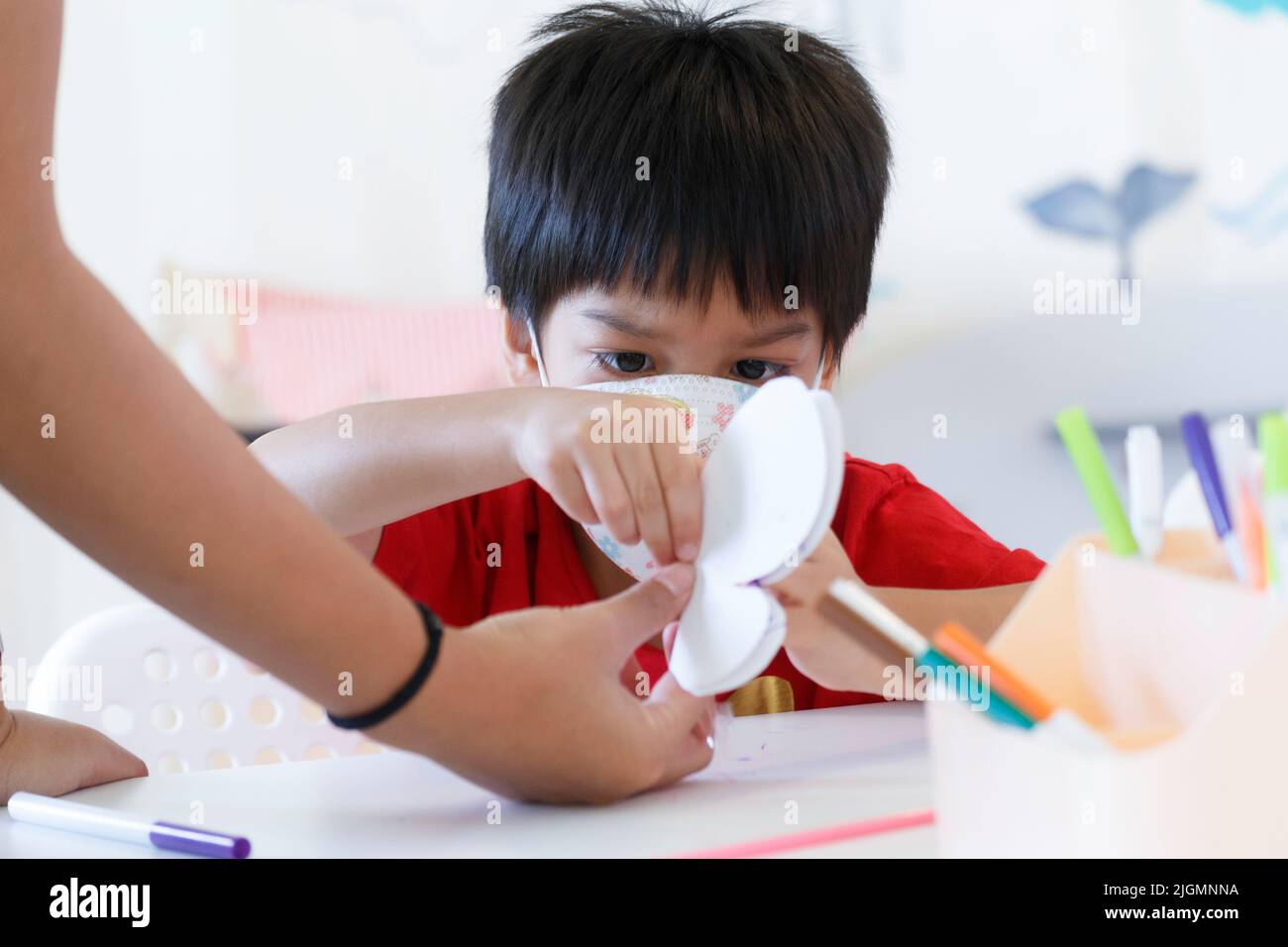 Little kid holding butterfly paper. Asia student boy learning to crafting diy butterfly paper from teacher in nursery classroom at kindergarten school Stock Photo