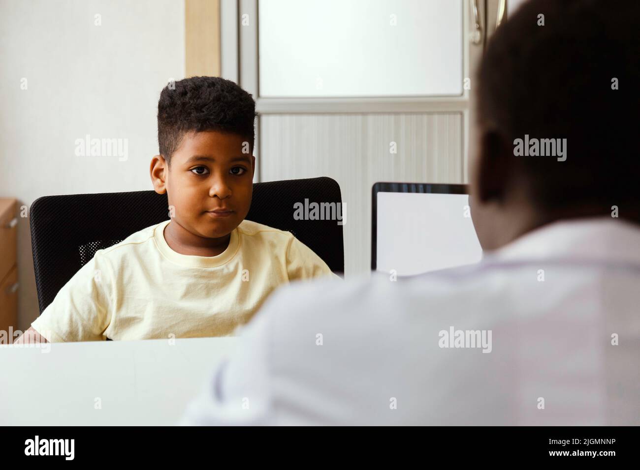 african american pediatrician or psychologist doctor talking to young boy patient in the office at the hospital. medical and healthy lifestyle concept Stock Photo