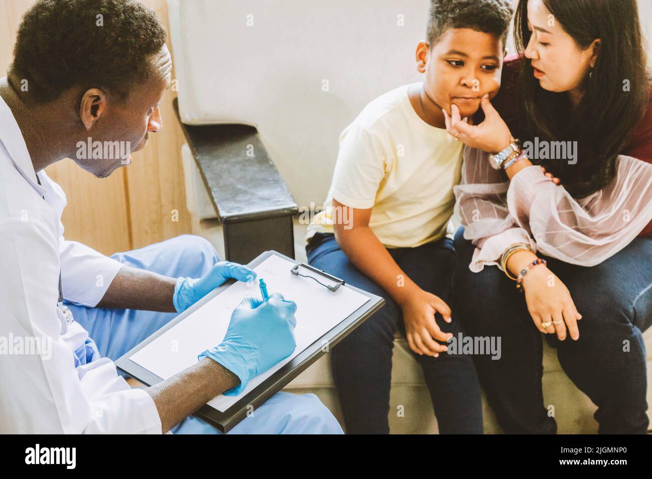 family psychologist. asian mother and her boy talk to african american psychotherapist doctor during therapy session at the hospital. Stock Photo