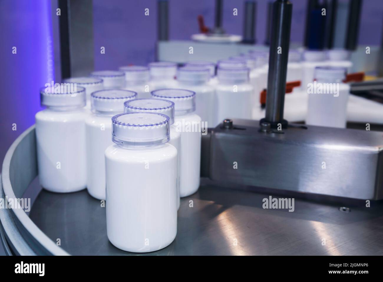 medicine or cosmetic white plastic bottle on the production line of the conveyor belt at filling machine in the healthcare manufacturing. Stock Photo