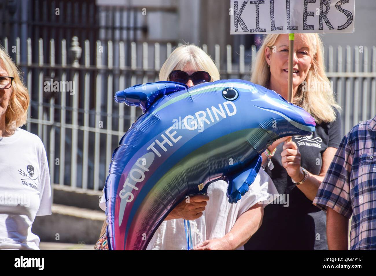 London, UK. 11th July, 2022. A protester holds a dolphin-shaped balloon with the message 'Stop the Grind' during the demonstration. Ocean and marine wildlife conservation organization Sea Shepherd staged a rally outside the Parliament as MPs debated a petition to suspend trade with the Faroe Islands until they end brutal whale and dolphin hunts, known as the 'Grind'. (Photo by Vuk Valcic/SOPA Images/Sipa USA) Credit: Sipa USA/Alamy Live News Stock Photo
