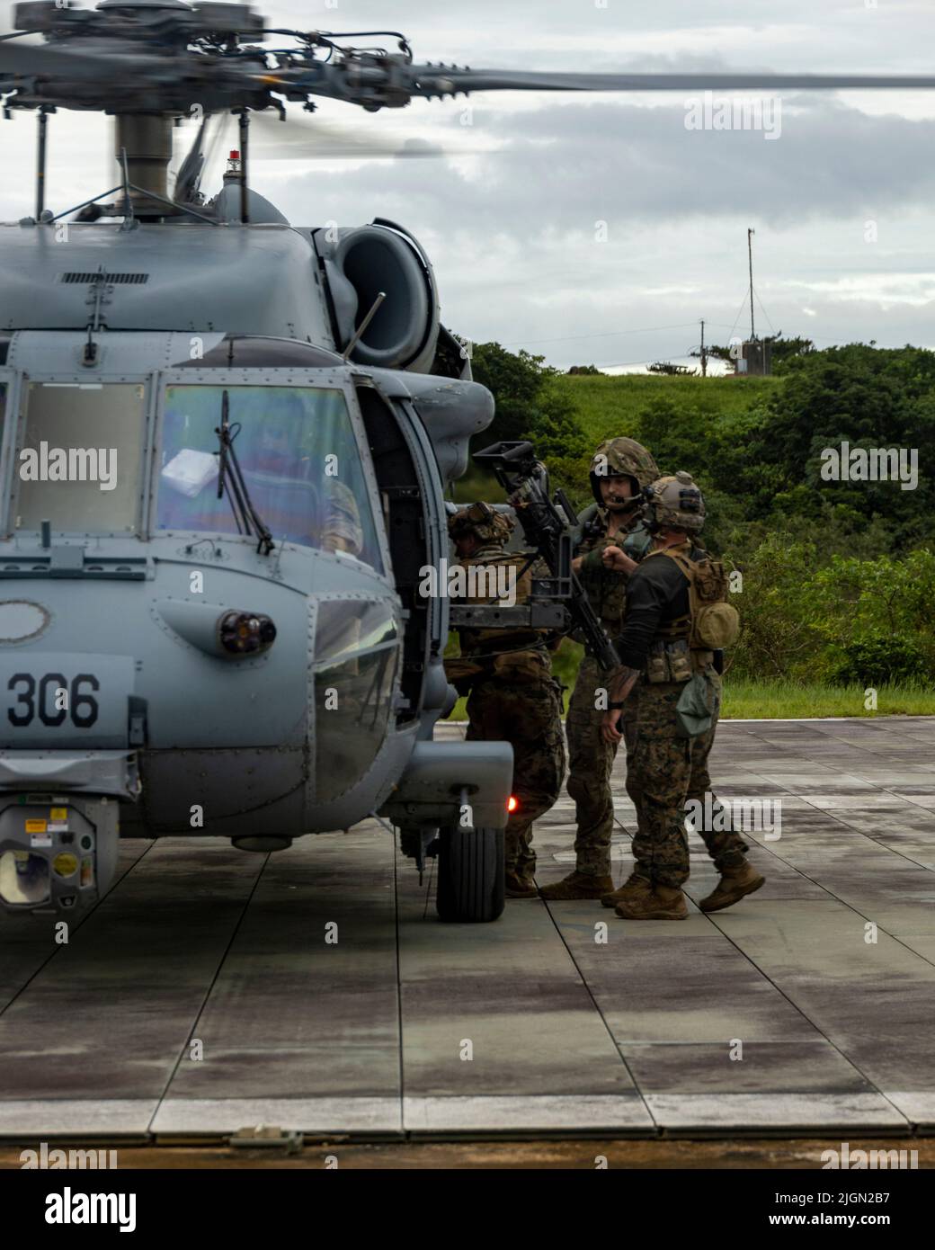 U.S. service members exit a U.S. Navy Sikorsky SH-60 Seahawk Helicopter with Helicopter Sea Combat Squadron 85, after an aerial sniper training during an Urban Sniper Course on Camp Schwab, Okinawa, Japan, June 15, 2022. The aerial sniper training was led by Marines and military contractors with the Expeditionary Operations Training Group to enhance participating Marines' skills in urban environments through precision fire and engaging simulated targets from an aircraft. (U.S. Marine Corps photo by Lance Cpl. Jonathan Beauchamp) Stock Photo