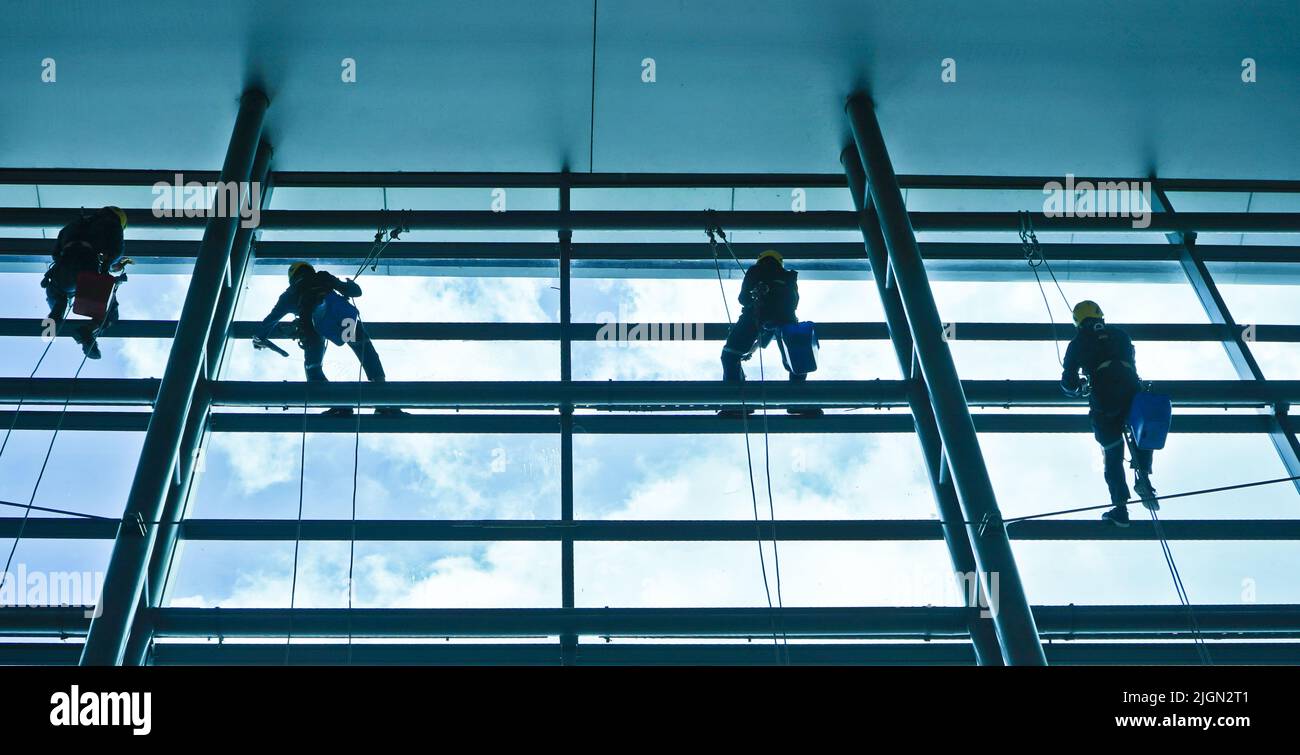 Extreme work. Cleaning the glass of a building at a height takes courage and challenges adrenaline Stock Photo