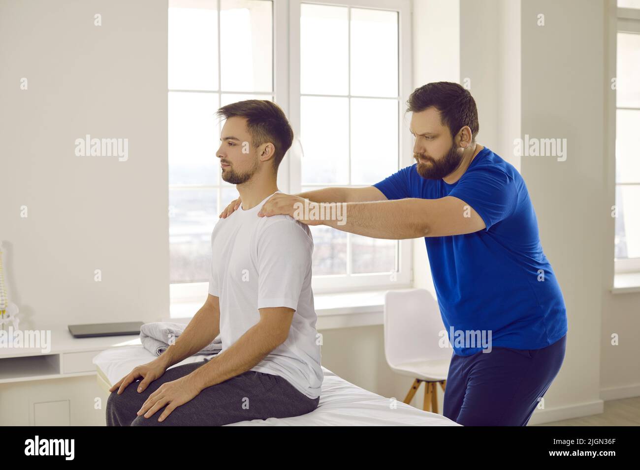 Masseur help patient massage back relieve spasm Stock Photo