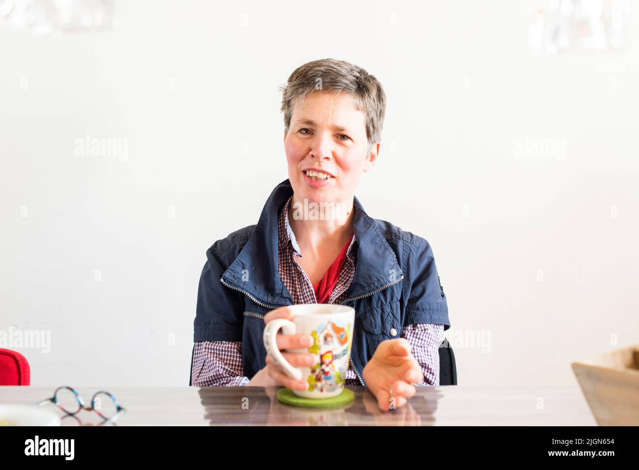 Tilburg, Netherlands. Mid adult caucasian woman, having multiple sclerosis or MS for over a decade, dealing with her disease by taking in healthy liquids and tea. Stock Photo