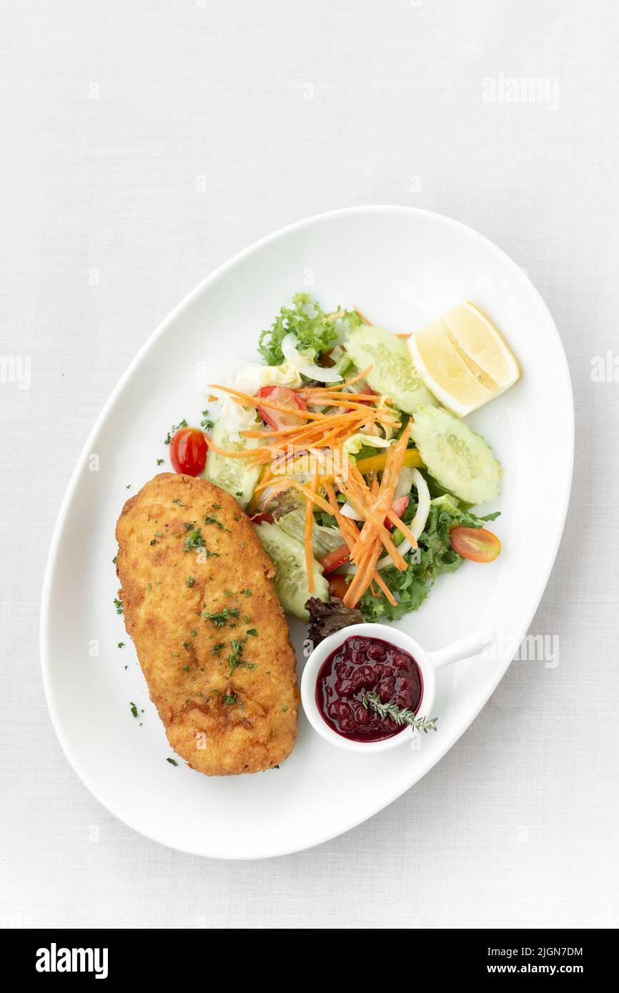 chicken cordon bleu with salad and cranberry sauce on white background Stock Photo