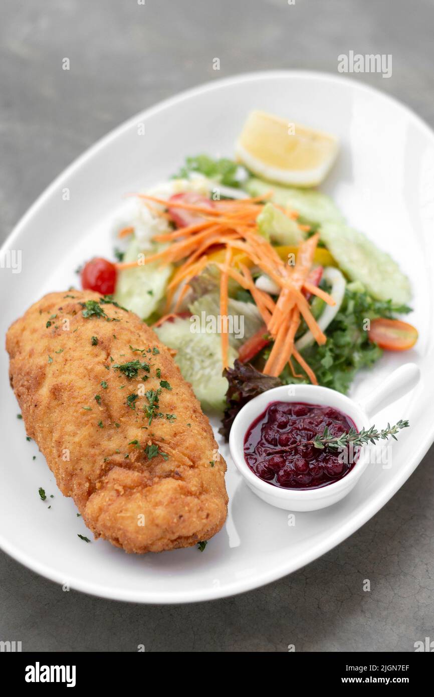 chicken cordon bleu meal with salad and cranberry sauce on grey background Stock Photo