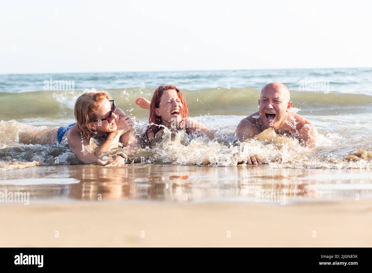 A family of three - father, mother and daughter are lying on the beach and enjoying a joint vacation. The family is lying on the seashore and enjoying Stock Photo