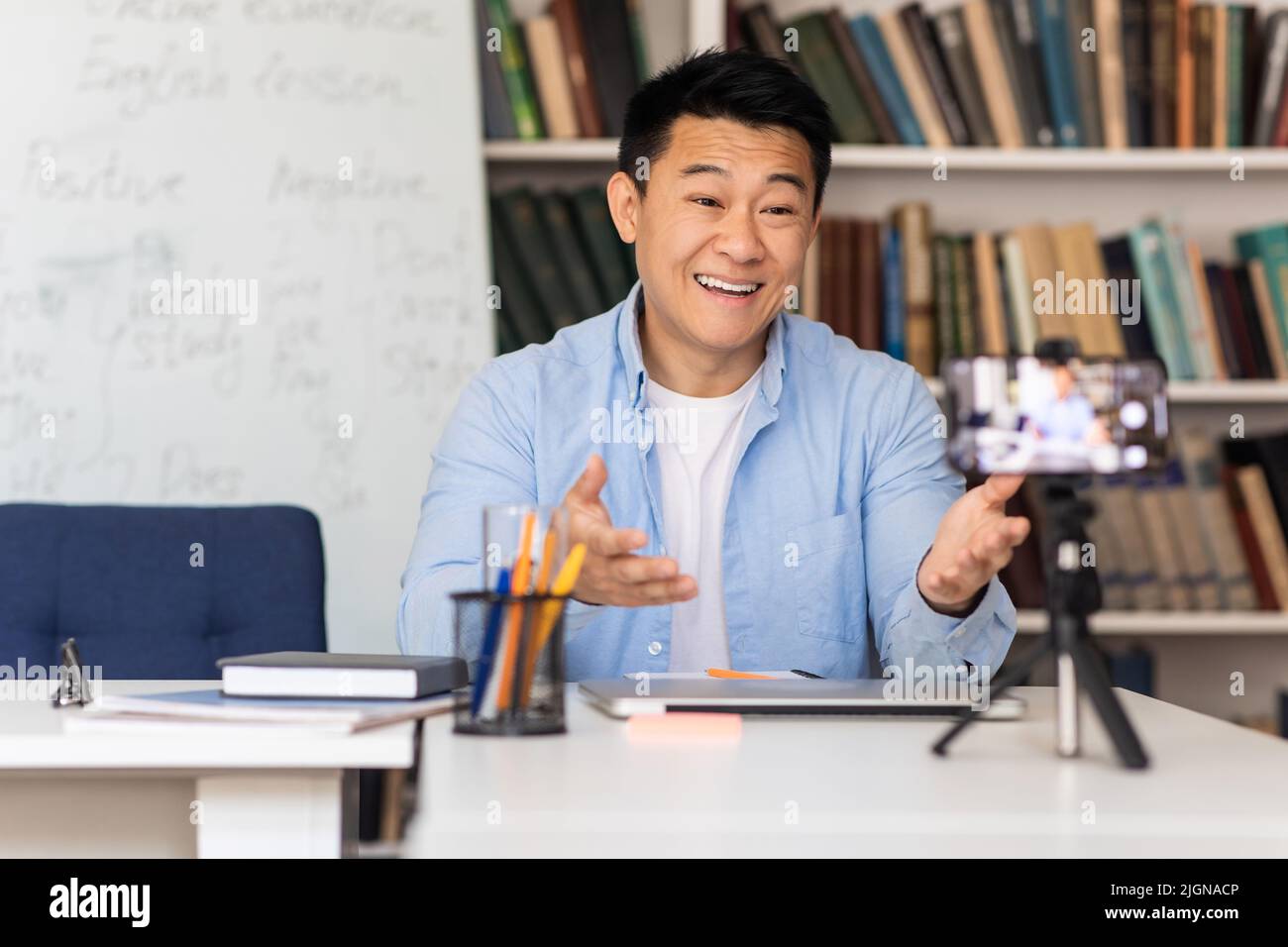 Japanese Male Tutor Having Class Via Video Call At Workplace Stock Photo