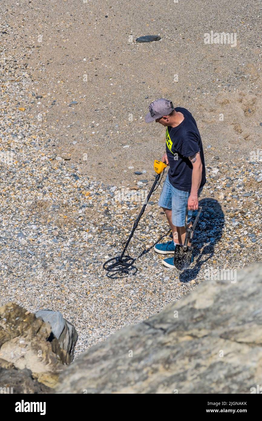 A metal detectorist searching on a beach in Cornwall in the UK Stock
