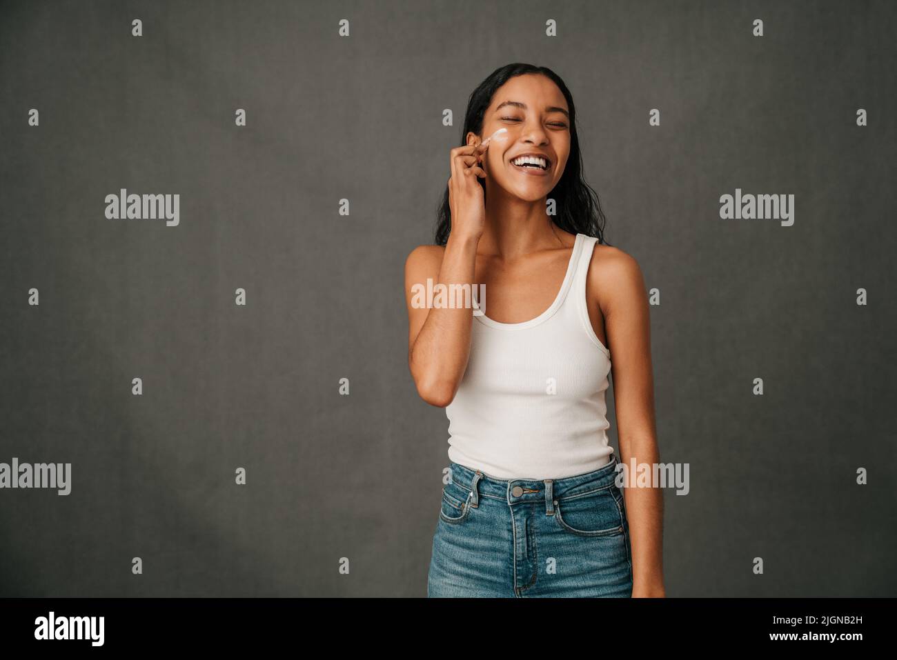 Smiling African American applying face cream to her face Stock Photo