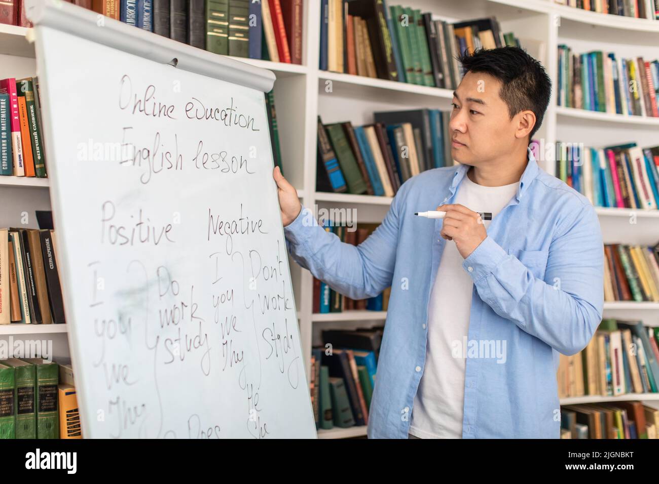 Chinese Teacher Man Teaching Writing On Whiteboard In Modern Classroom Stock Photo