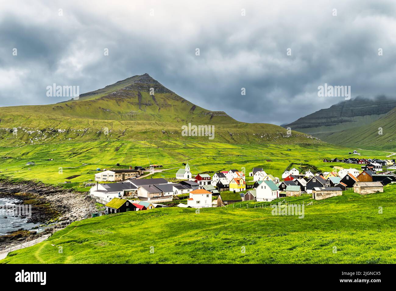 Colorful houses of Gjogv village and a small river flows into fjord. Faroe Islands Stock Photo