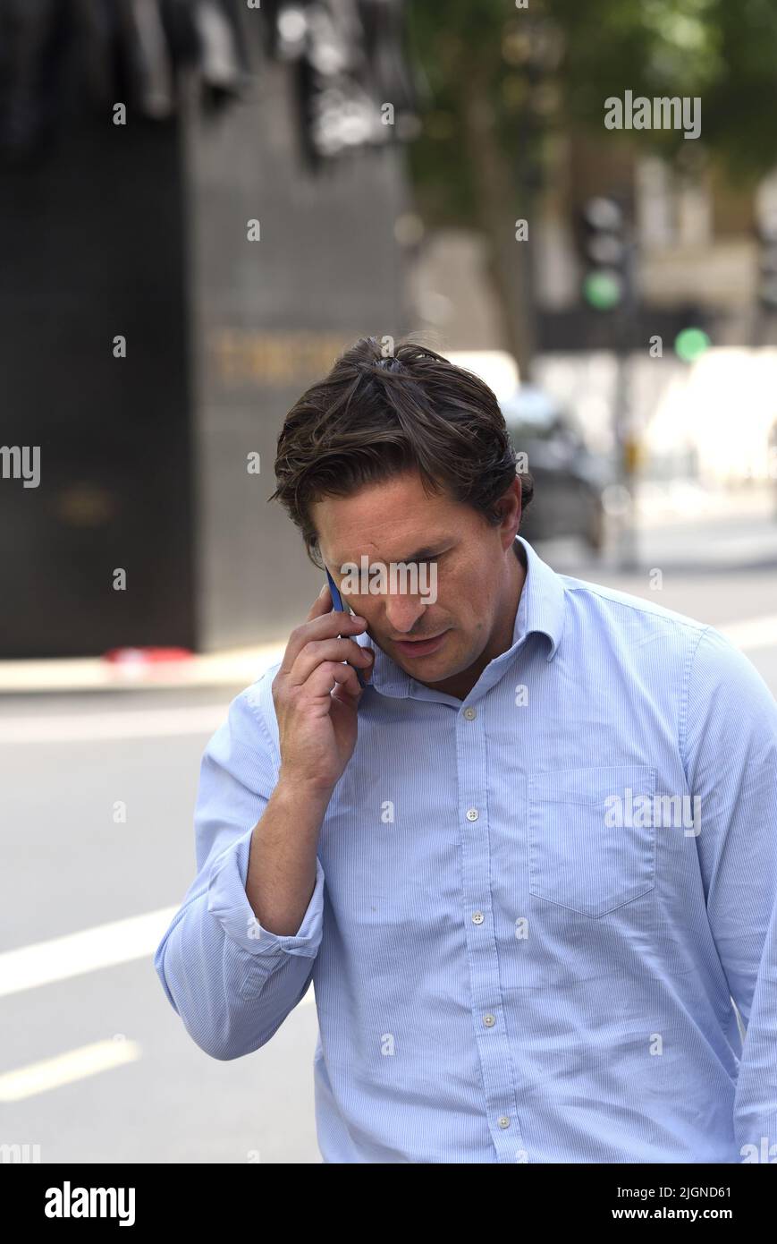 Johnny Mercer MP (Con: Plymouth Moor) - Minister for Veterans' Affairs - on his mobile phone outside the Cabinet Office, walking past the Women of WW' Stock Photo