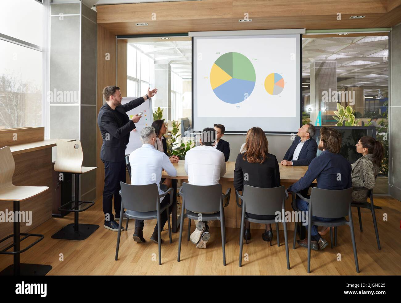 Manager shows his colleagues business presentation with data analysis on screen in modern office. Stock Photo