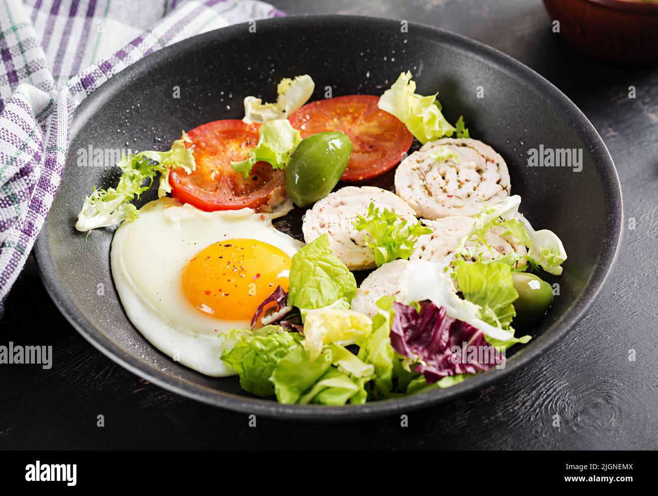 Fried egg, meat roll, olives and tomatoes. Keto, paleo breakfast. Ketogenic menu. Stock Photo