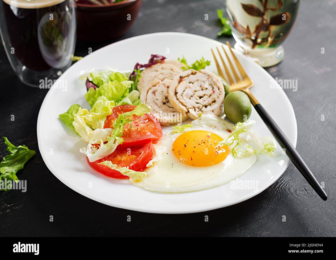 Fried egg, meat chicken roll, olives and tomatoes. Keto, paleo breakfast. Ketogenic food. Stock Photo