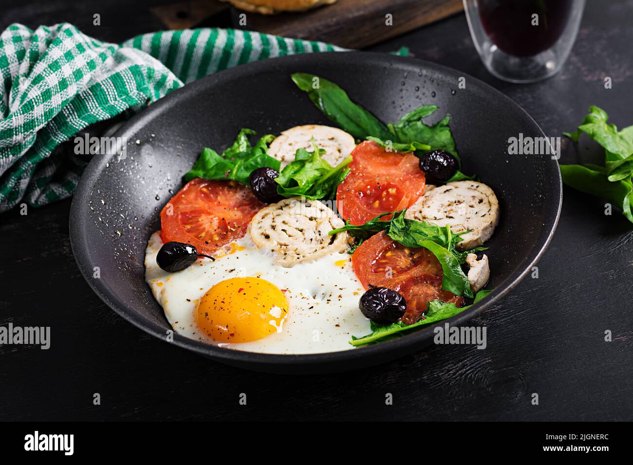 Fried egg, meat roll, black olives,  tomatoes and spinach. Keto breakfast. Ketogenic menu. Stock Photo