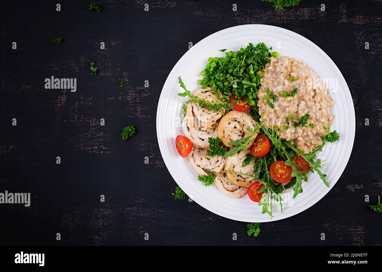 Brunch or lunch. Plate with oatmeal, chicken fillet, tomato and green herbs. Health food. Top view, overhead Stock Photo
