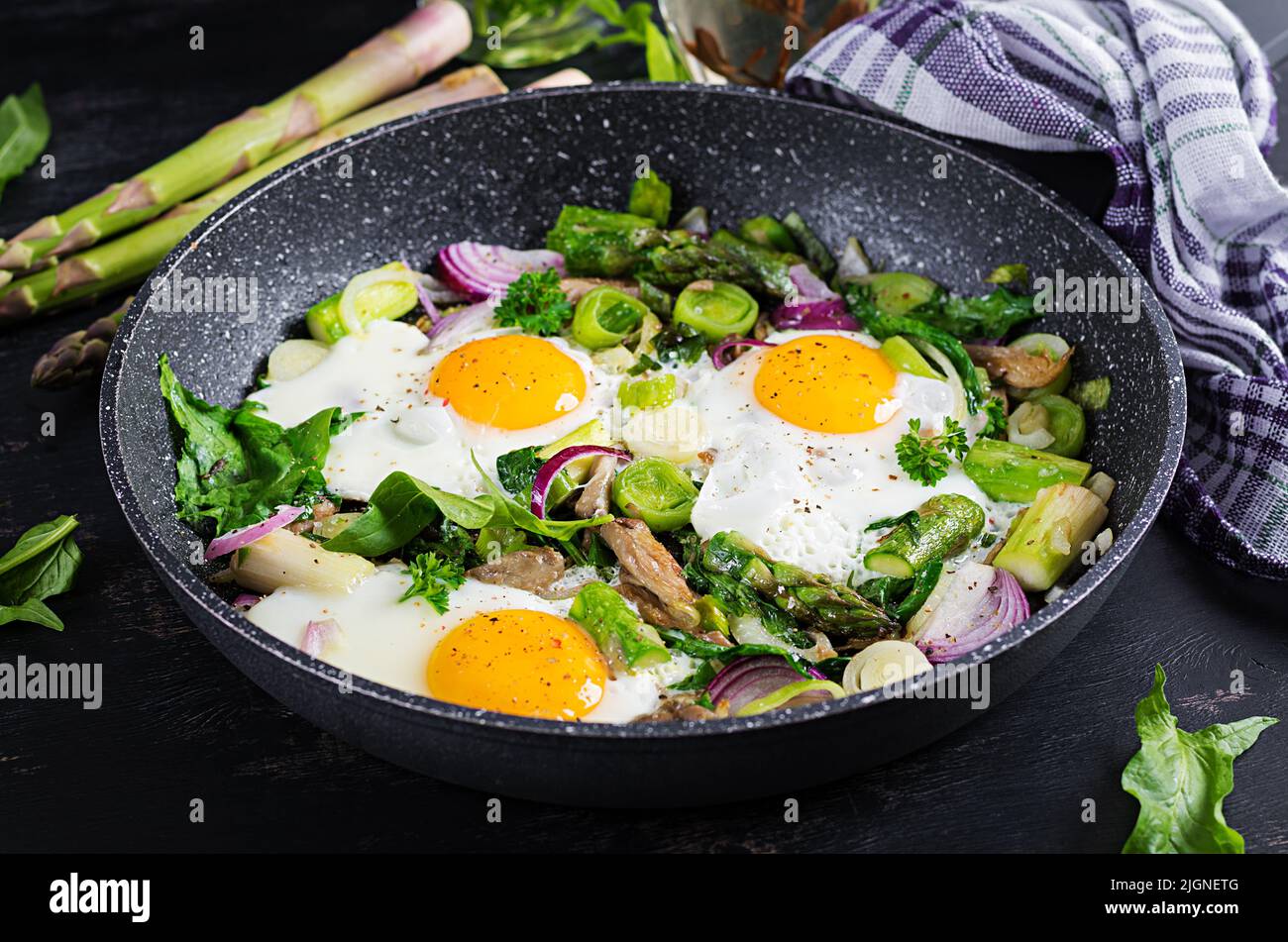 Fried eggs with asparagus, leeks, spinach and mushrooms. Useful breakfast. Stock Photo