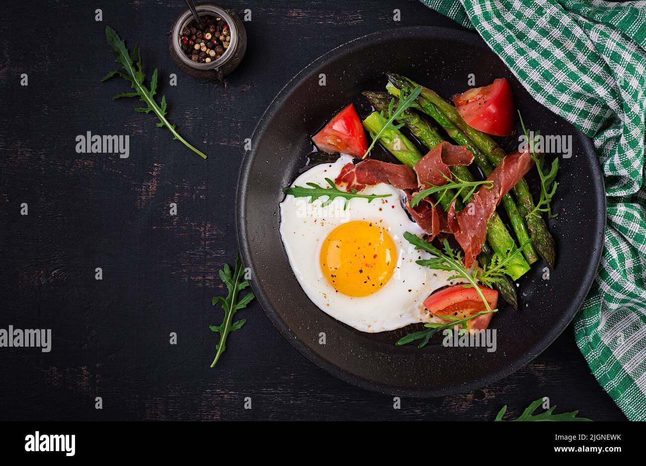 Fried egg with asparagus, tomato and bacon. Useful breakfast. Top view, overhead Stock Photo