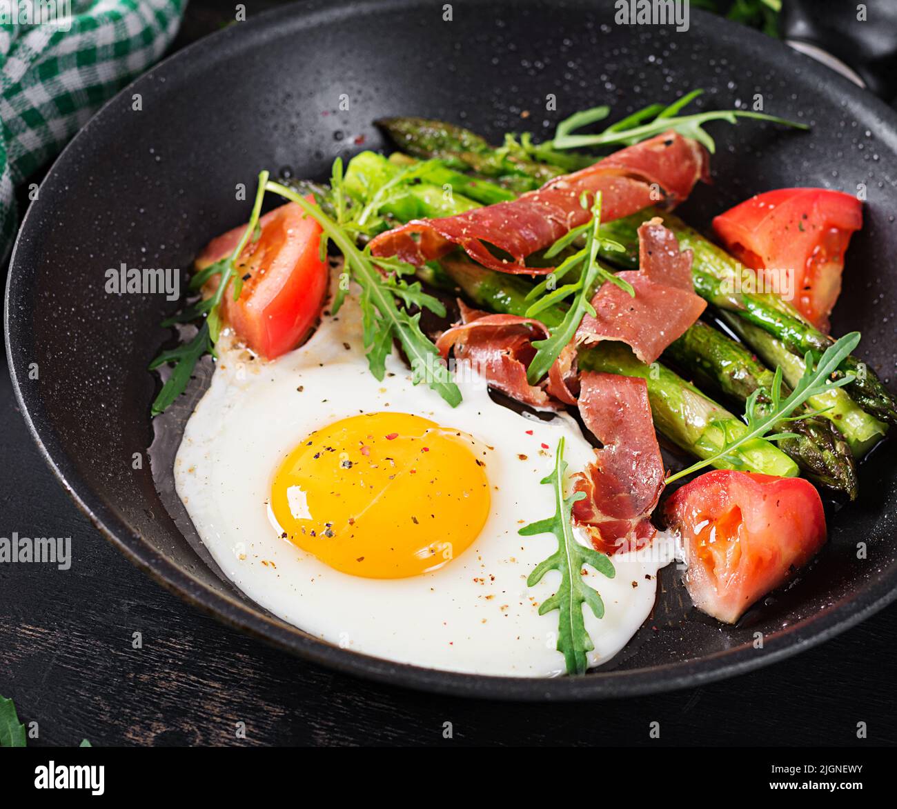 Fried egg with asparagus, tomato and bacon. Useful breakfast. Stock Photo