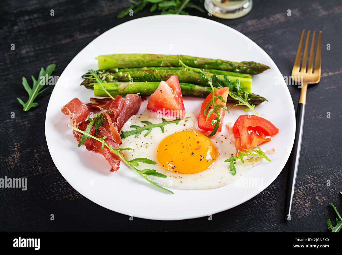 Fried egg with asparagus, tomato and bacon. Useful breakfast. Stock Photo