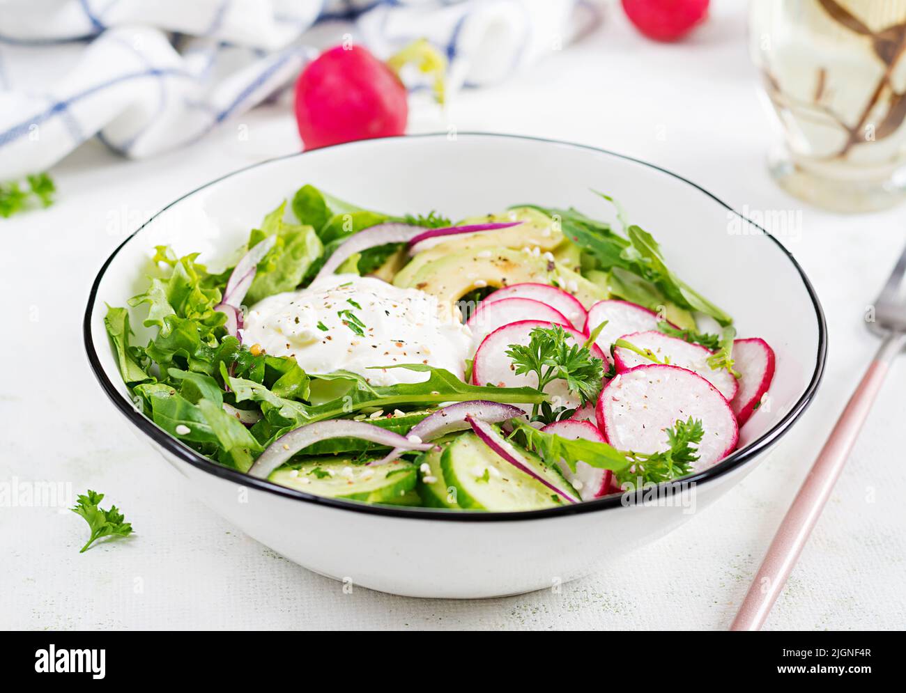 Vegetarian vegetable salad of radish, cucumbers, avocado and yogurt.  Healthy vegan food. Stock Photo