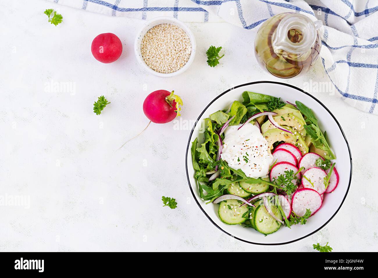 Vegetarian vegetable salad of radish, cucumbers, avocado and yogurt.  Healthy vegan food. Top view, above Stock Photo