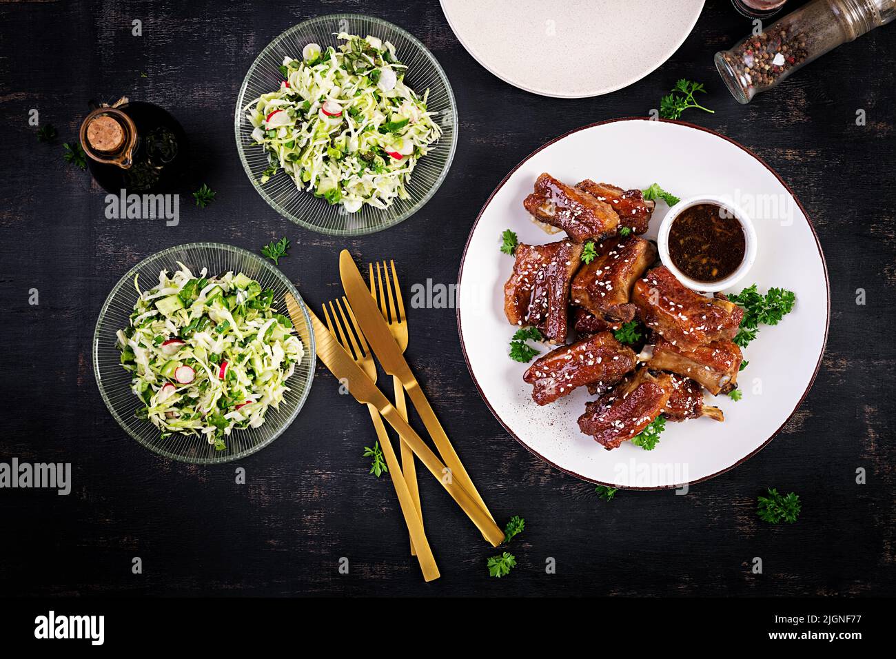 Delicious barbecued spare ribs on plate on dark background. Tasty bbq meat. Top view, flat lay Stock Photo