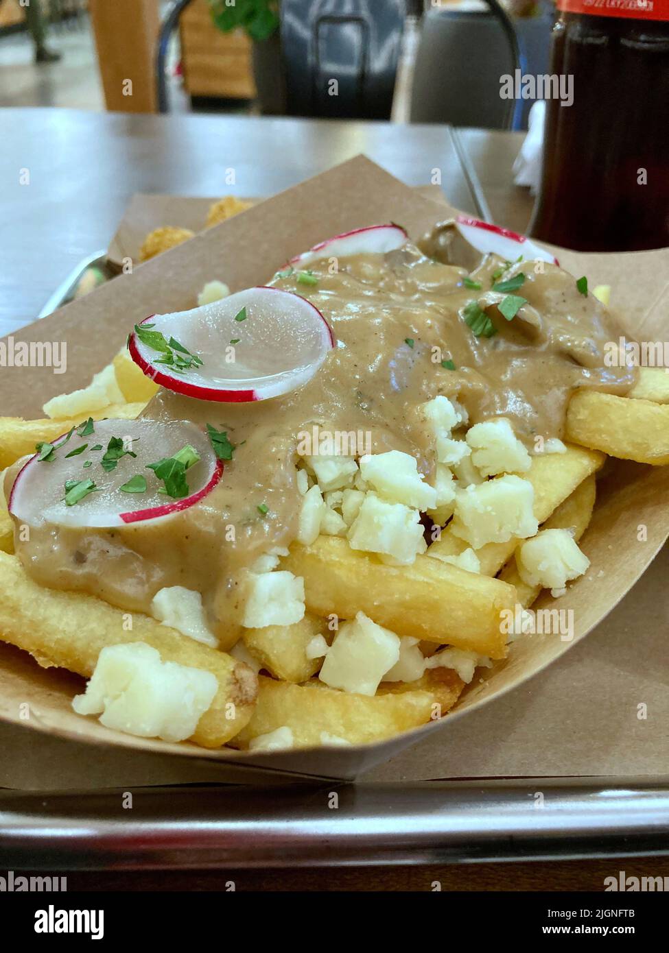 delicious poutine, french fries with gravy or sauce garnish with cheese and reddish Stock Photo
