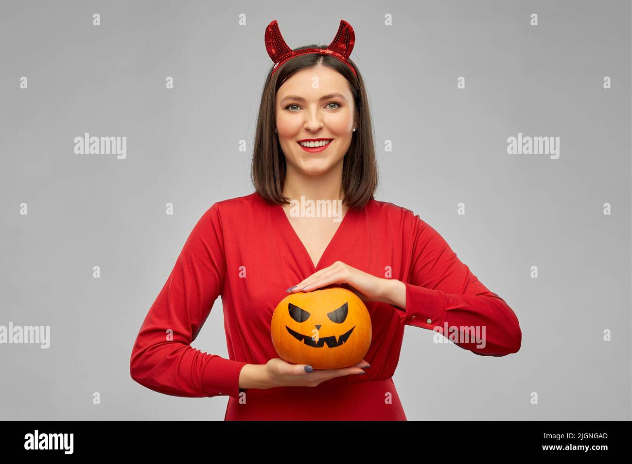 woman in halloween costume of devil with pumpkin Stock Photo