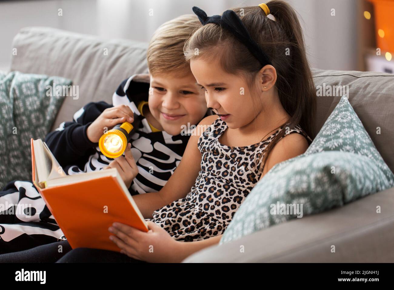 kids in halloween costumes reading book at home Stock Photo Alamy