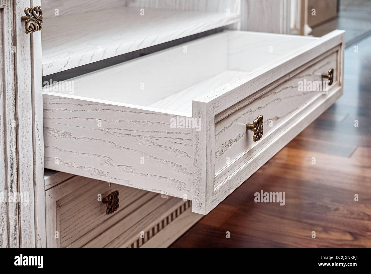 Built-in chest of drawers from veneer and solid ash in light enamel with gray patina. Detail of decorative wall in room Stock Photo