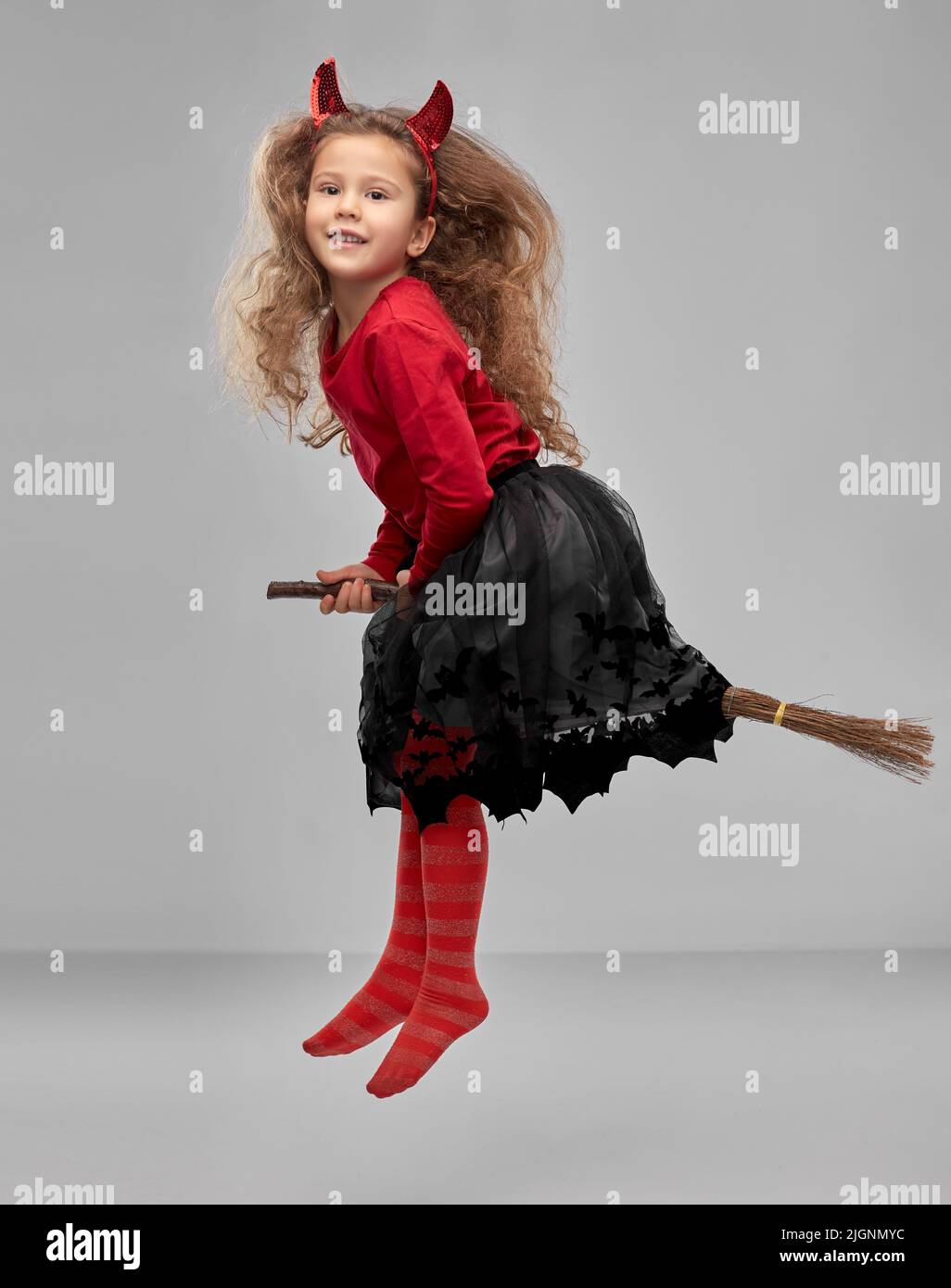 girl in halloween costume flying with witch broom Stock Photo